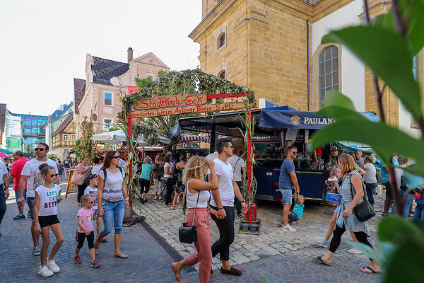 Auf dem Bild sind Menschen zu sehen, die an in der Innenstadt aufgestellten Verzehrständen vorbeilaufen.