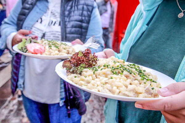 Auf dem Bild sind zwei Teller mit Käsespätzle zu sehen. 