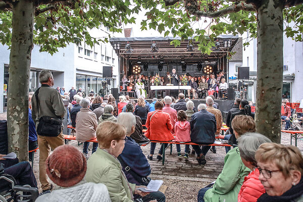 Auf dem Bild sind Menschen beim Gottesdienst im freien zu sehen.