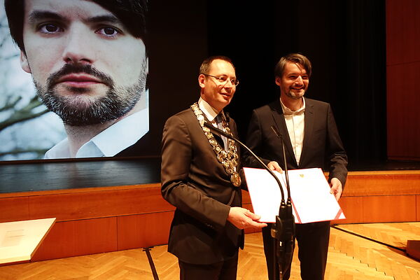 Auf dem Bild ist der damalige Oberbürgermeister Thilo Rentschler und der Schubart-Literaturpreisträger zu sehen, die eine Urkunde in die Kamera halten.
