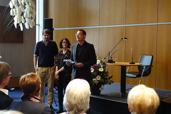 Auf dem Bild sind die beiden Preisträger*innen bei der Schubart-Literaturpreis-Verleihung mit dem damaligen Oberbürgermeister Thilo Rentschler zu sehen.