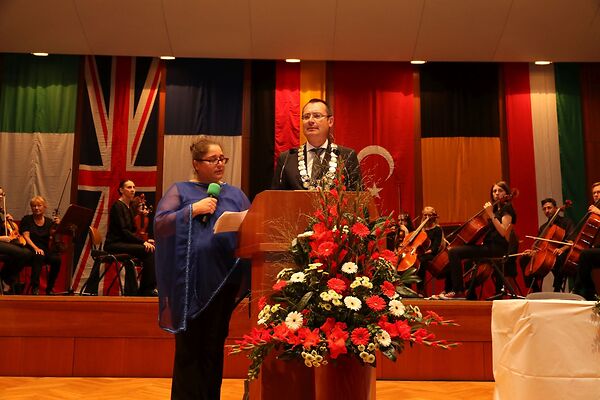 Auf dem Bild ist der damalige Oberbürgermeister Thilo Rentschler an einem Rednerpult zu sehen. Neben ihm steht eine Frau mit einem Mikrofon und im Hintergrund ist ein Orchester zu sehen.