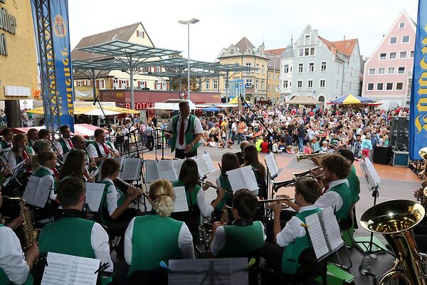 Auf dem Bild sind die musizierenden Mitglieder eines Orchesters auf einer Bühne am Gmünder Torplatz zu sehen.