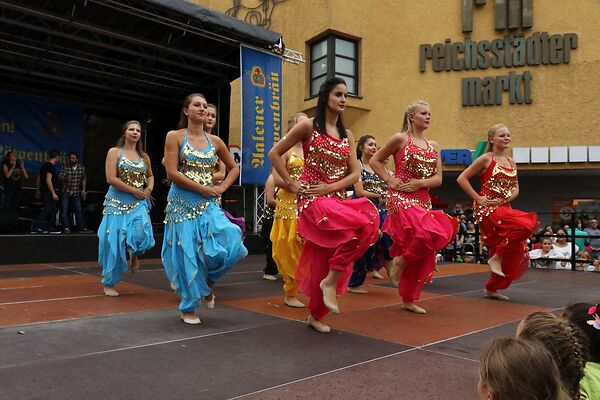 Auf dem Bild sind in bunten Gewändern gekleidete Tänzerinnen auf einer Bühne am Gmünder Torplatz zu sehen.