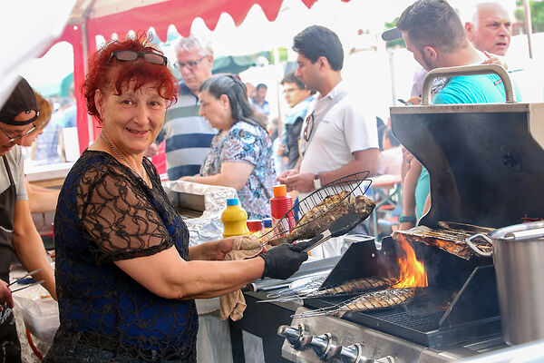 Auf dem Bild ist eine Frau zu sehen, die Fisch auf einem Grill zubereitet.