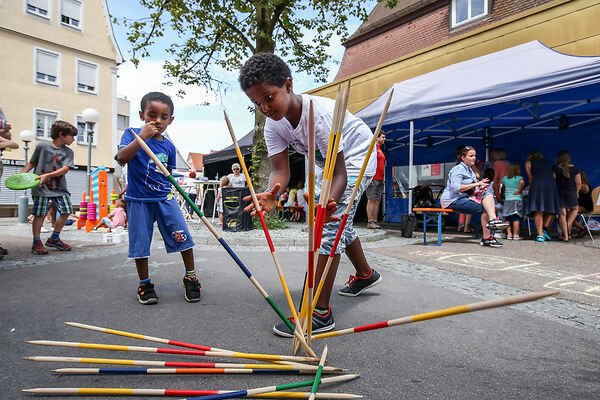 Auf dem Bild sind zwei Kinder zu sehen, die Mikado spielen.