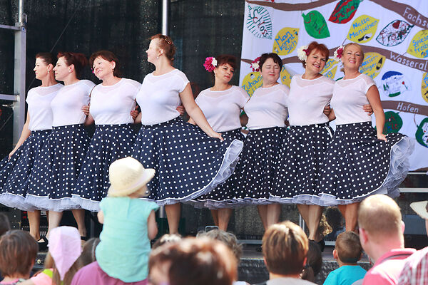 Auf dem Bild ist eine Gruppe von Frauen zu sehen, die auf einer Bühne tanzen.