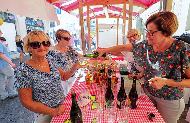 Auf dem Bild sind Frauen zu sehen, die für andere Frauen Wein ausschenken.