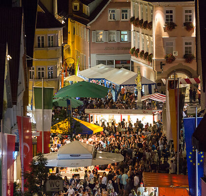 Auf dem Bild ist die mit Menschen gefüllte Aalener Innenstadt bei Dunkelheit zu sehen.