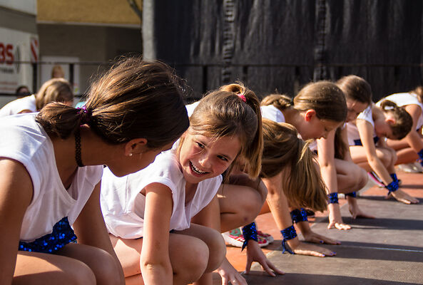 Auf dem Bild sind Mädchen zu sehen die innerhalb einer Tanzchoreografie in einer Reihe auf dem Boden knien.