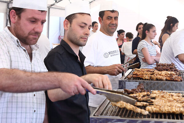 Auf dem Bild sind Männer zu sehen, die auf einem Grill Spieße anbraten.