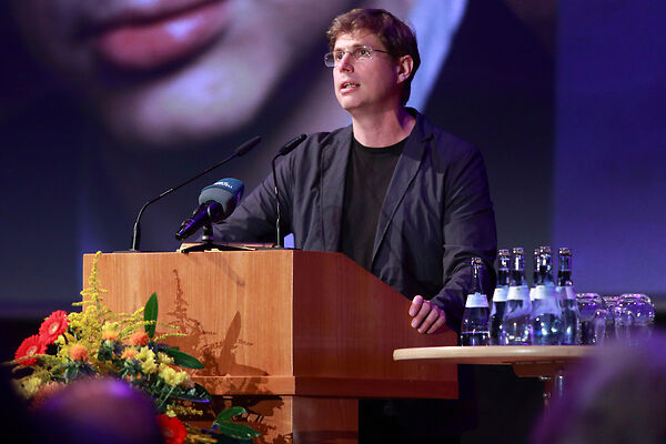Auf dem Bild ist der Schubart-Literaturpreisträger zu sehen, der an einem Rednerpult eine Rede hält.