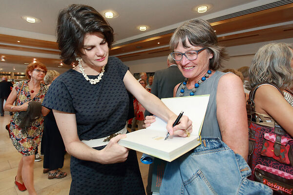 Auf dem Bild ist die Förderpreisträgerin zu sehen, die ein Buch von einer Frau signiert.