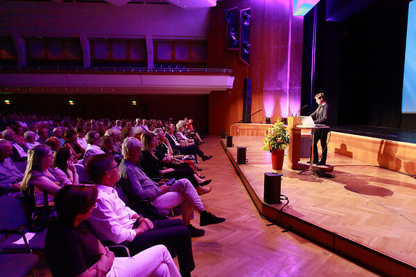Auf dem Bild ist der Schubart-Literaturpreisträger auf einer Bühne zu sehen, der eine Rede vor einem Publikum hält.