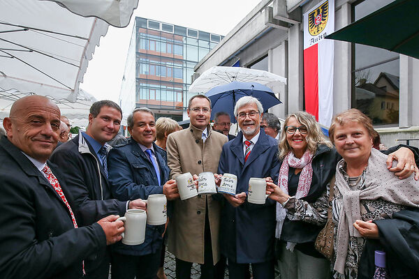 Auf dem Bild sind Männer und Frauen zu sehen, die mit Bierkrügen anstoßen.