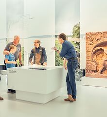 Auf dem Bild sind mehrere Menschen vor einem Schaukasten zu sehen.